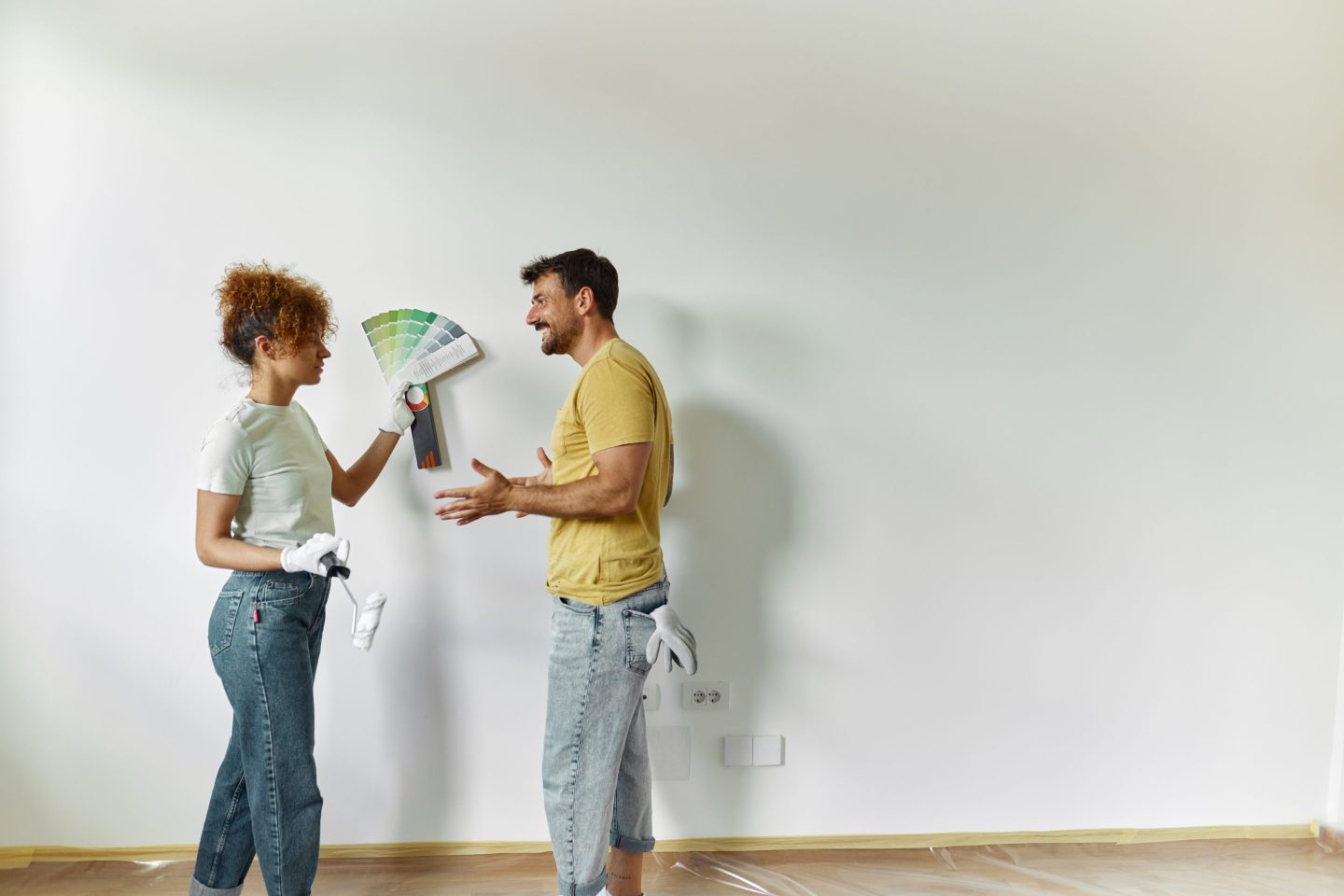 Young happy couple talking while choosing colors for the wall while renovating their apartment. Copy space.